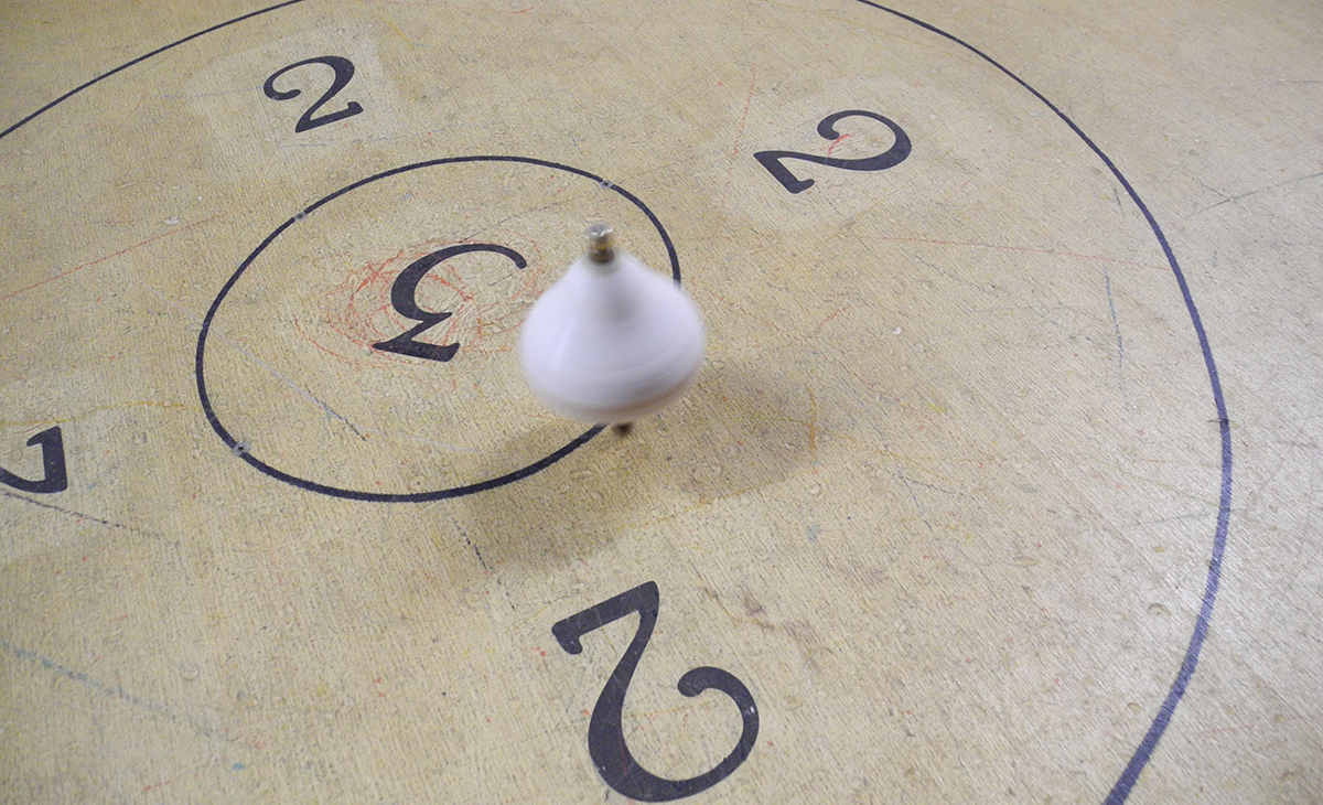Giochi in legno - trottola in legno che gira sulla pista tra i punteggi 2 e 3