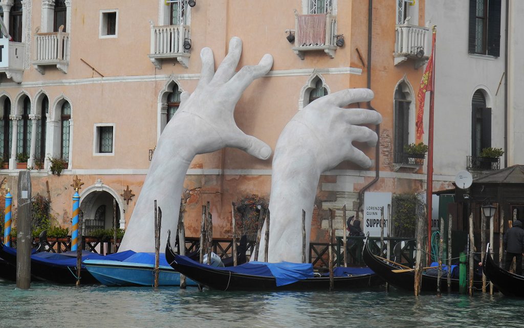 Venezia e il gioco - veduta della laguna con installazione di mani giganti