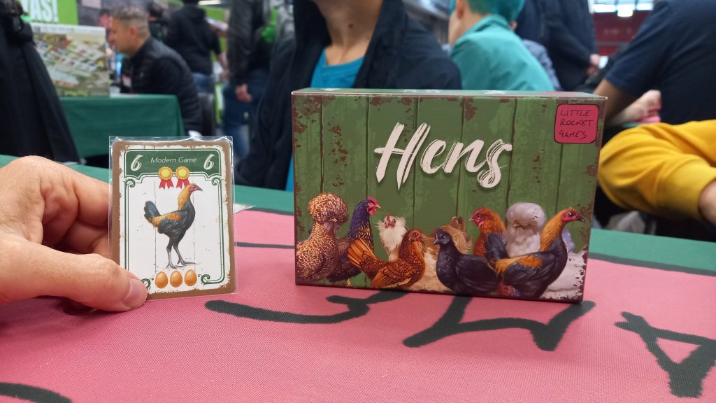 La scatola e una carta di "Hens" sul tavolo da gioco di Modena Play