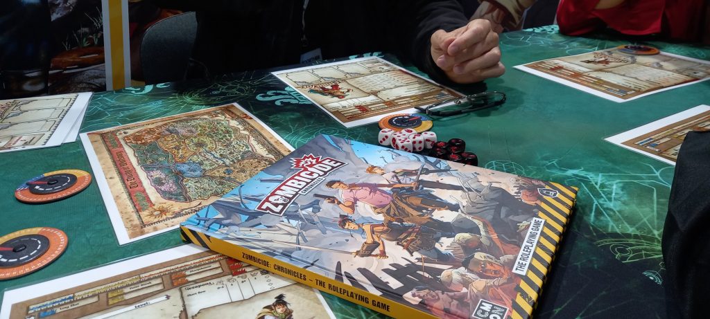 Tavolo di gioco con dadi, mappa e fogli giocatore dell'avventura Zombicide - i secoli bui