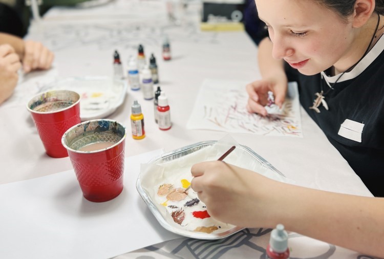 Una ragazza dipinge al laboratorio di pittura di miniature a Play Modena